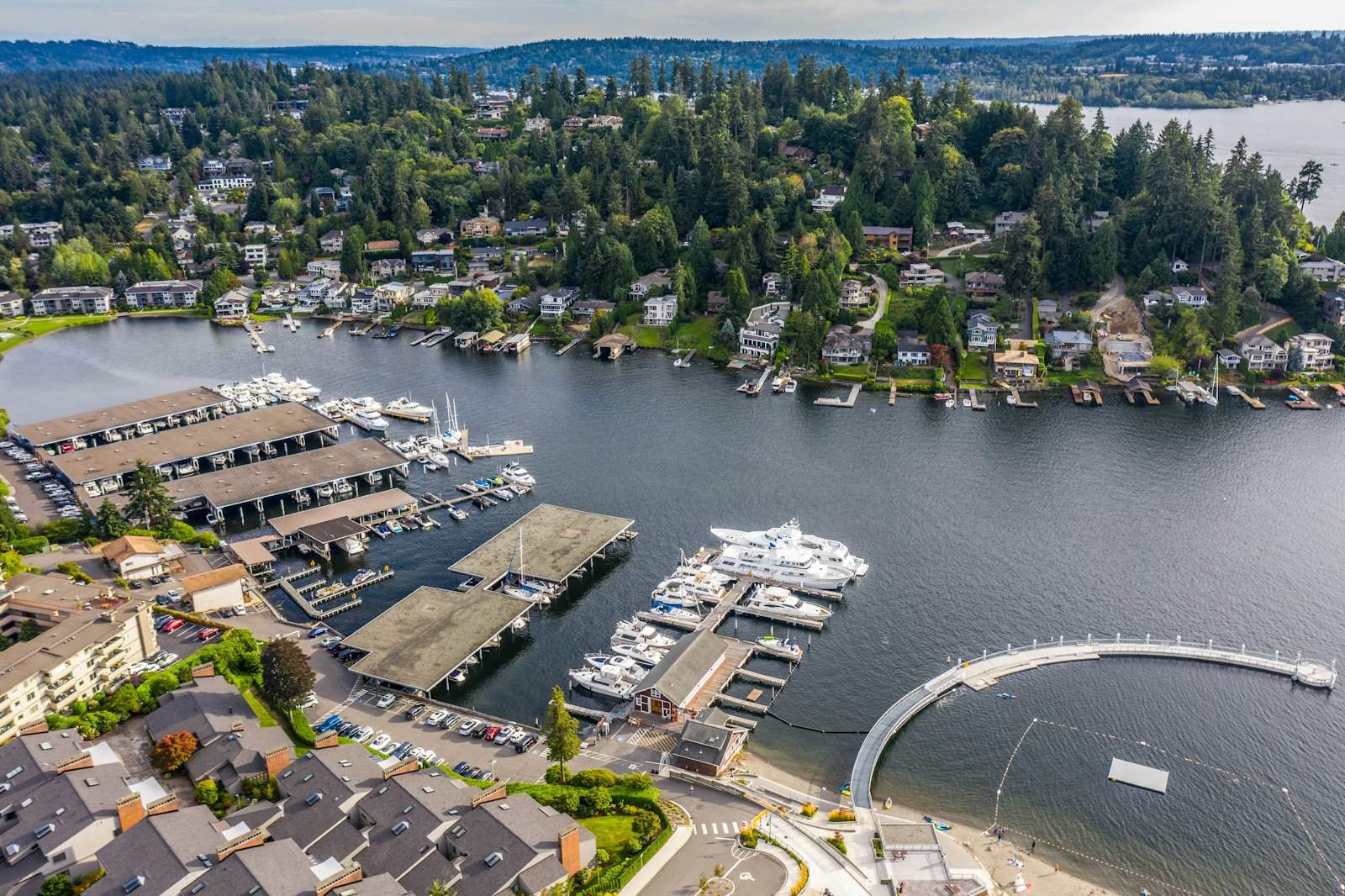 Aerial view of a marina, lakefront buildings and wooded neighborhoods