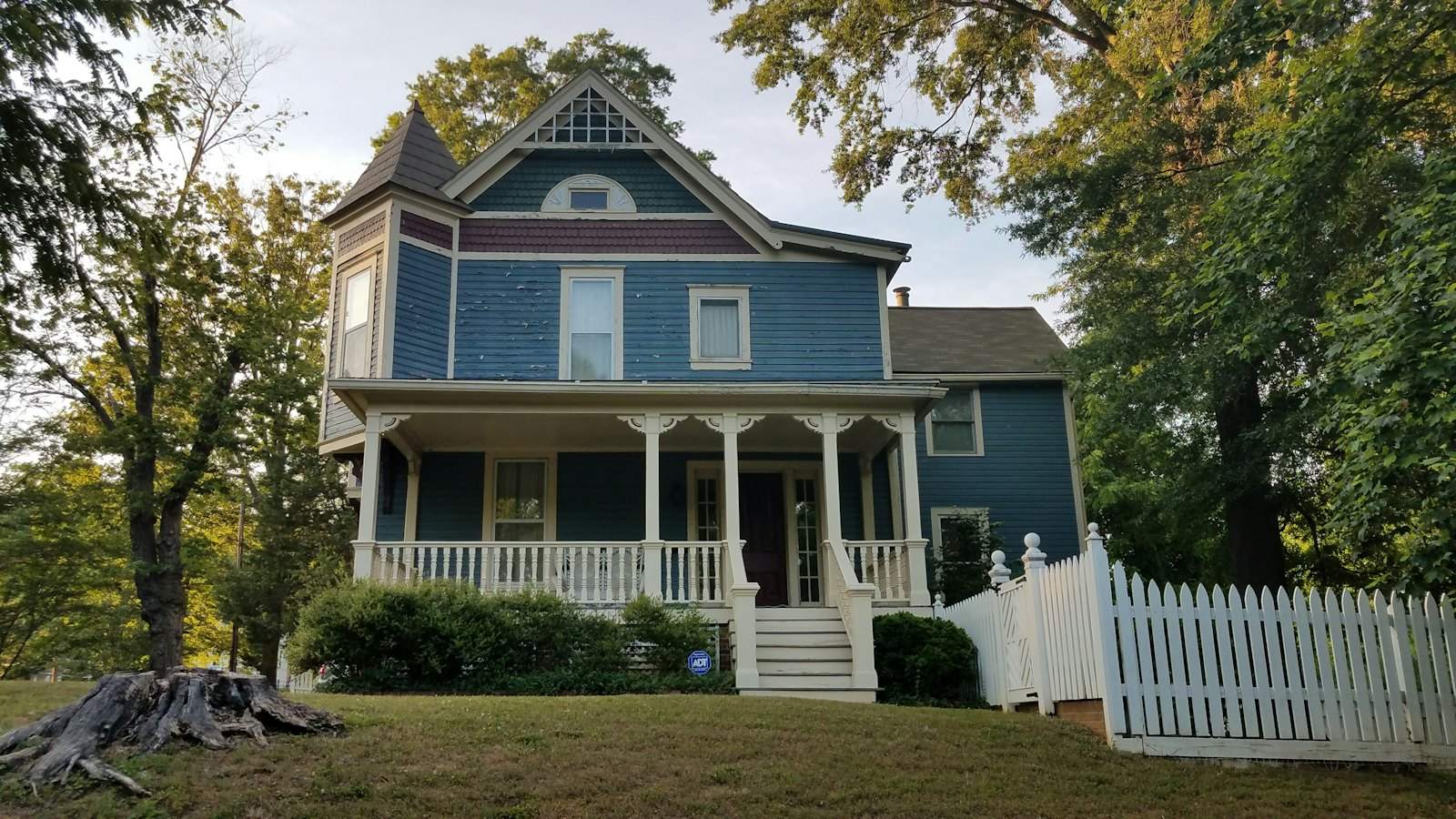 Blue Victorian house with a white porch and picket fence