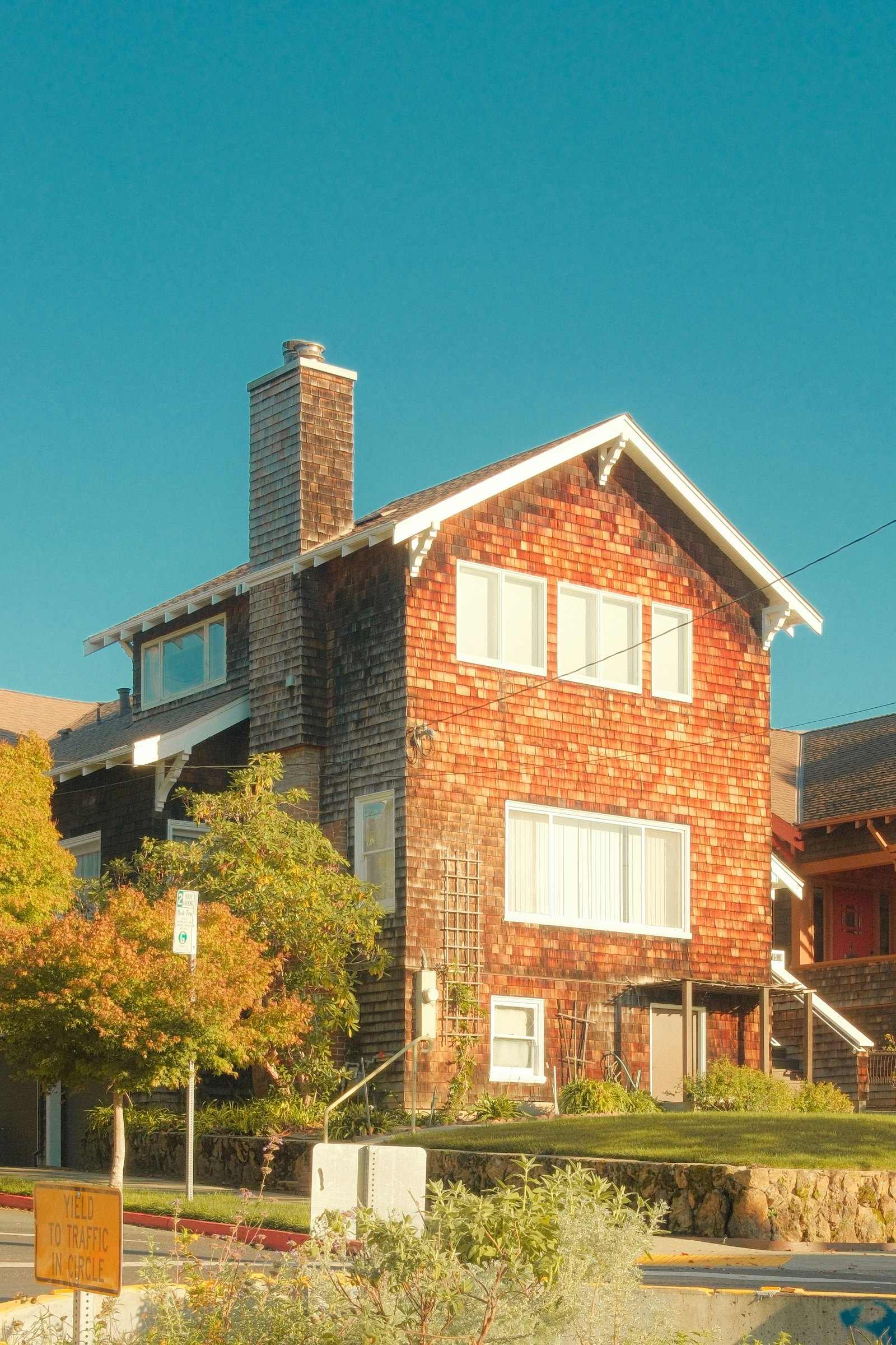 Two-story house with red cedar shingle siding and white windows
