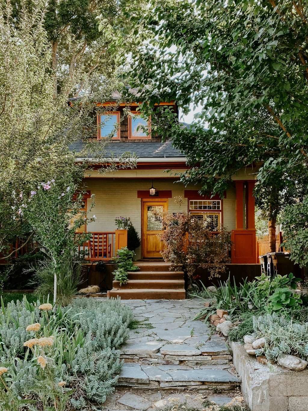 Craftsman house with a wooden front door behind a lush garden