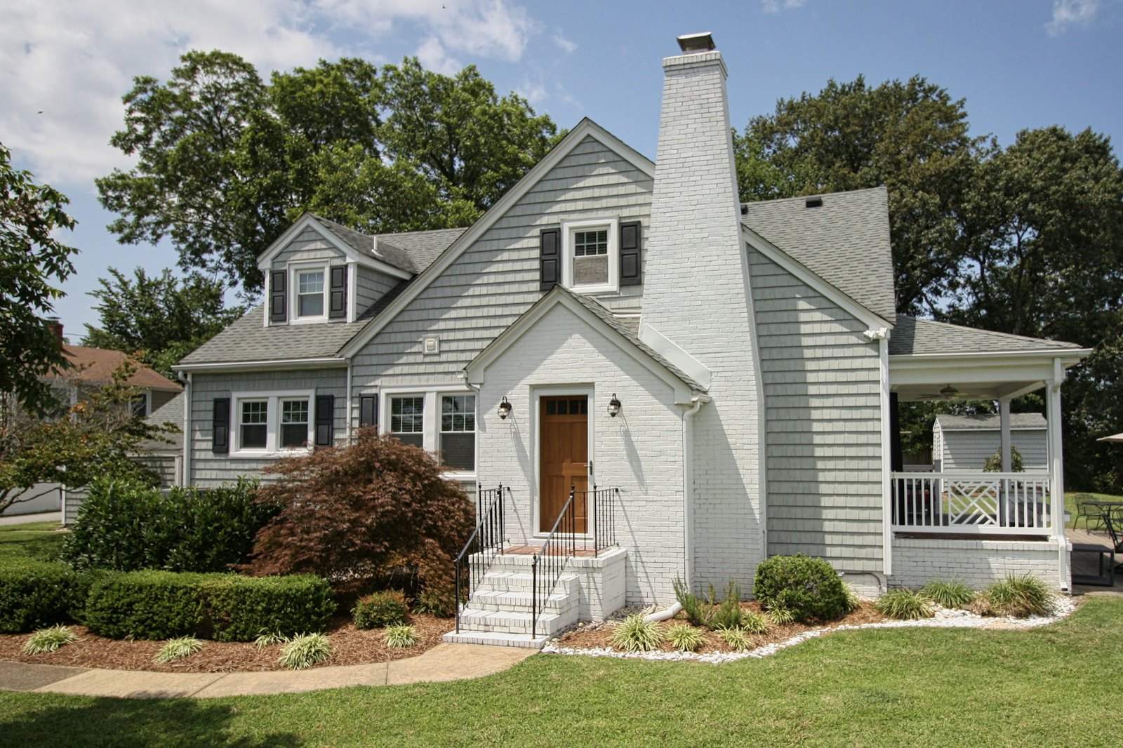 Gray cottage with a white brick chimney and a brown front door