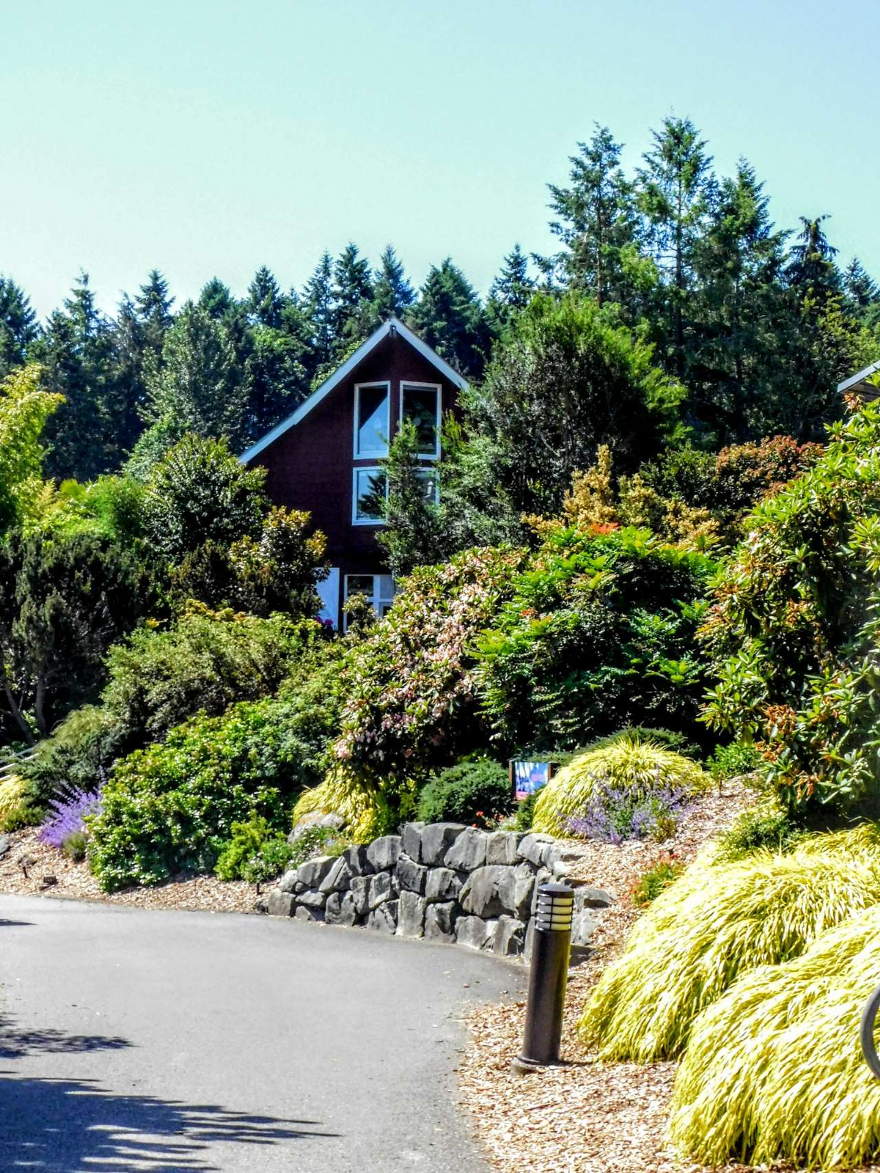 Maroon house on a hillside above a flowering garden