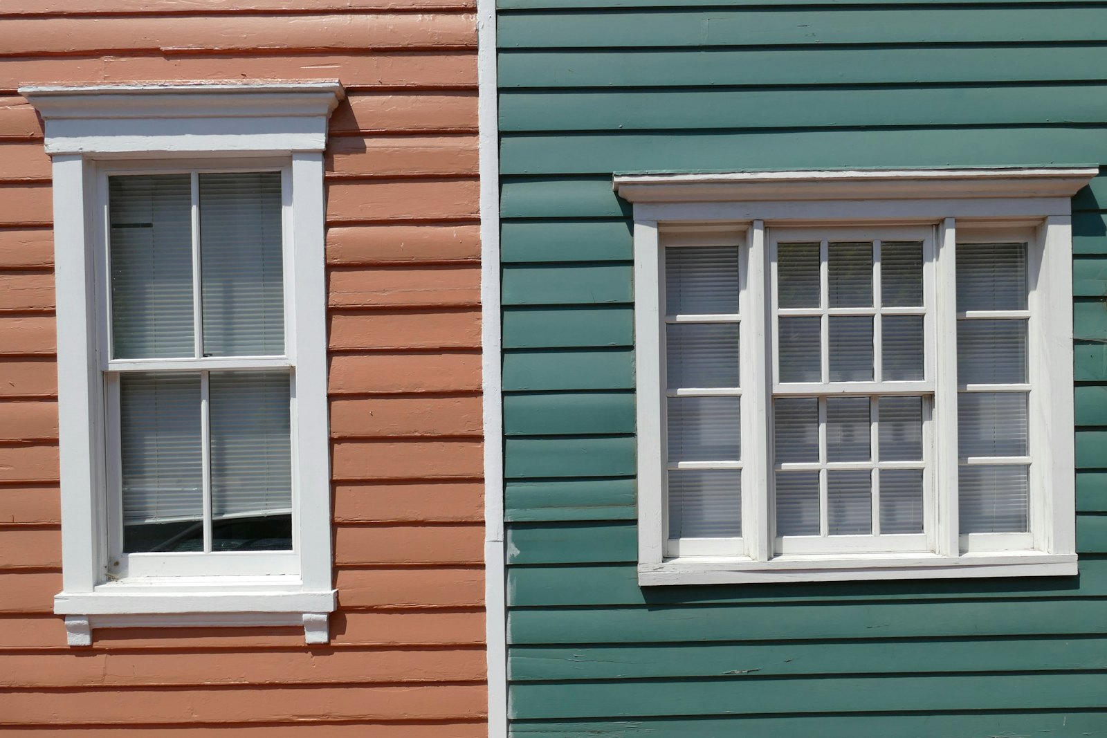 Red and green painted lap siding with white window trim side by side