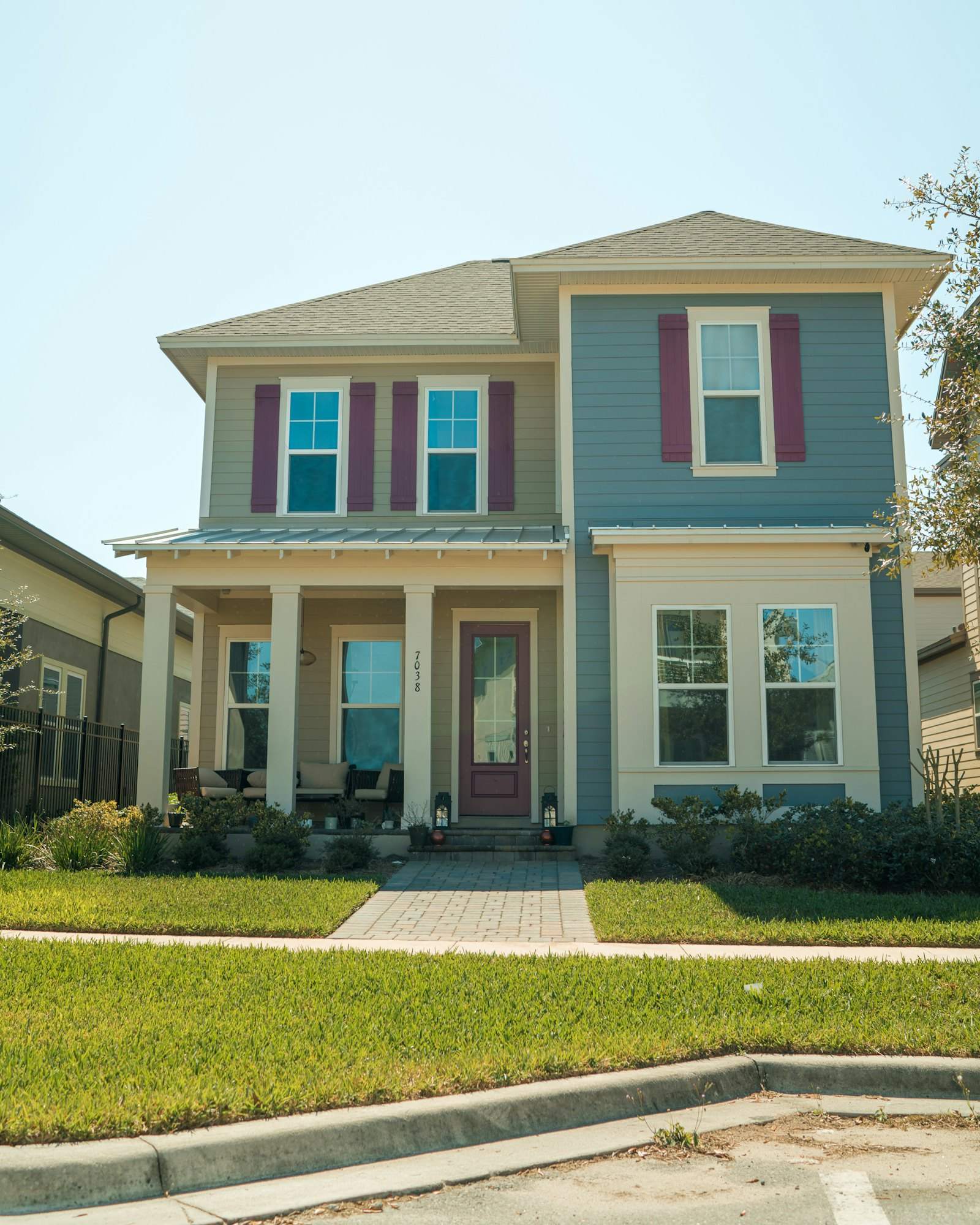 Two-story house with blue and tan siding, a front porch and red shutters