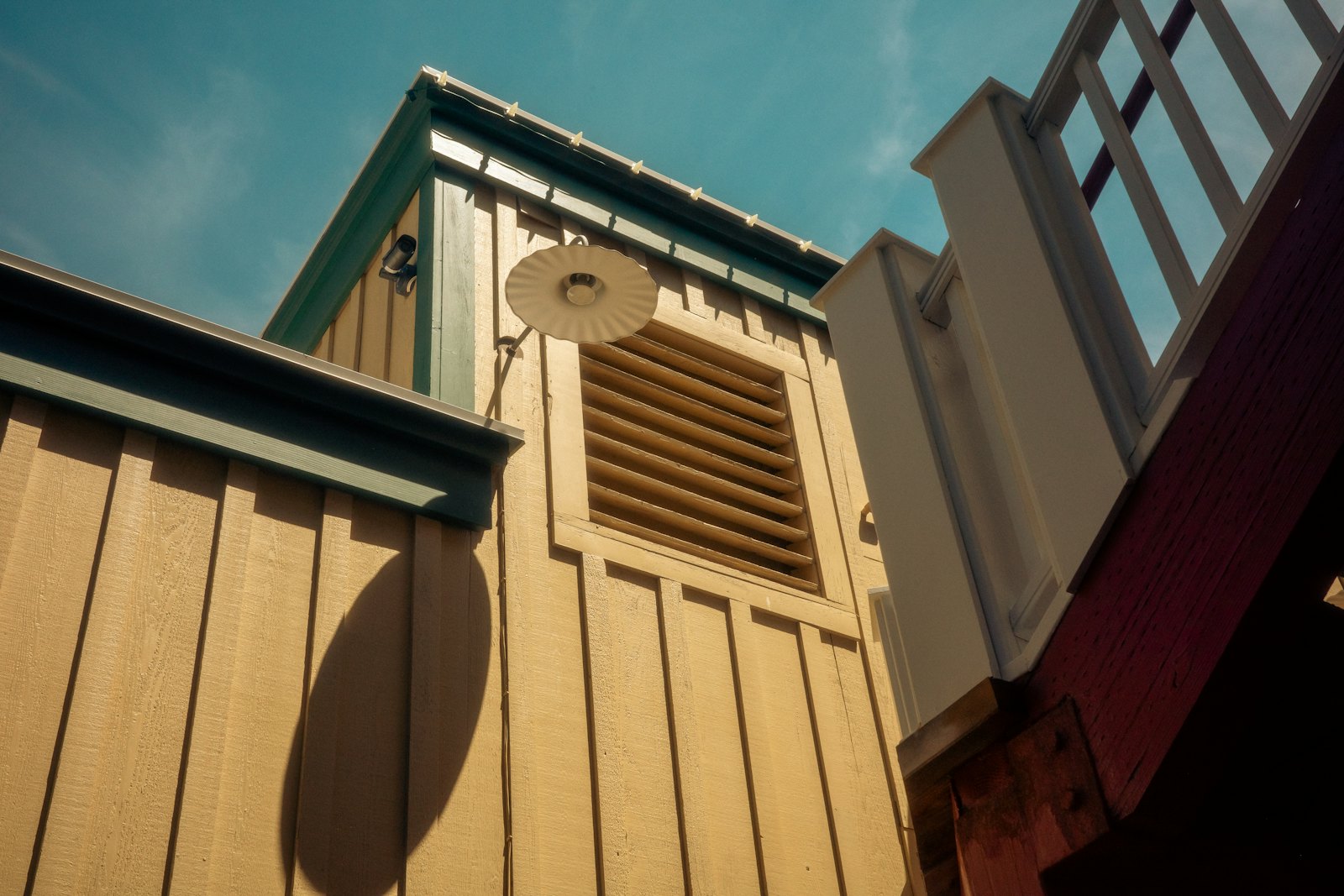 Yellow board-and-batten siding with green trim and a louvered vent