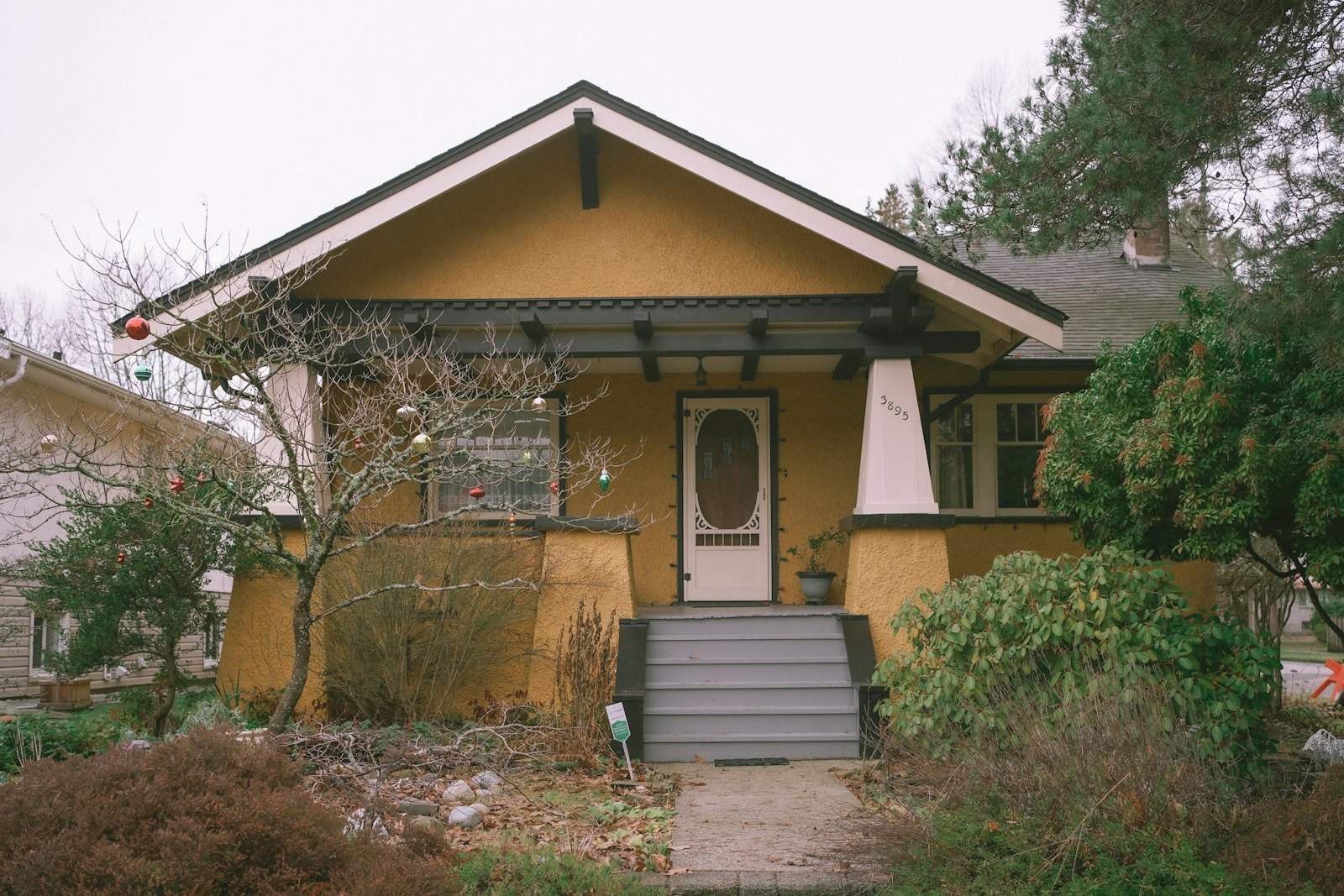 Yellow Craftsman bungalow with a gabled porch and front steps