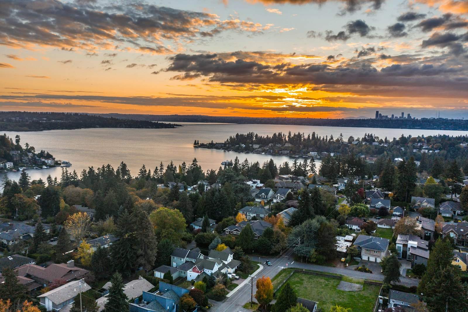 Aerial view of a wooded residential neighborhood on a lake at sunset