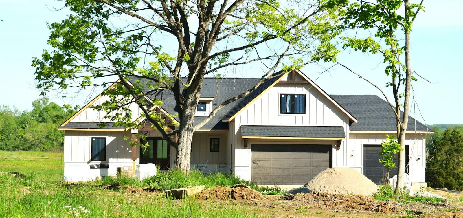 New home with white board-and-batten siding and a dark roof nearing completion