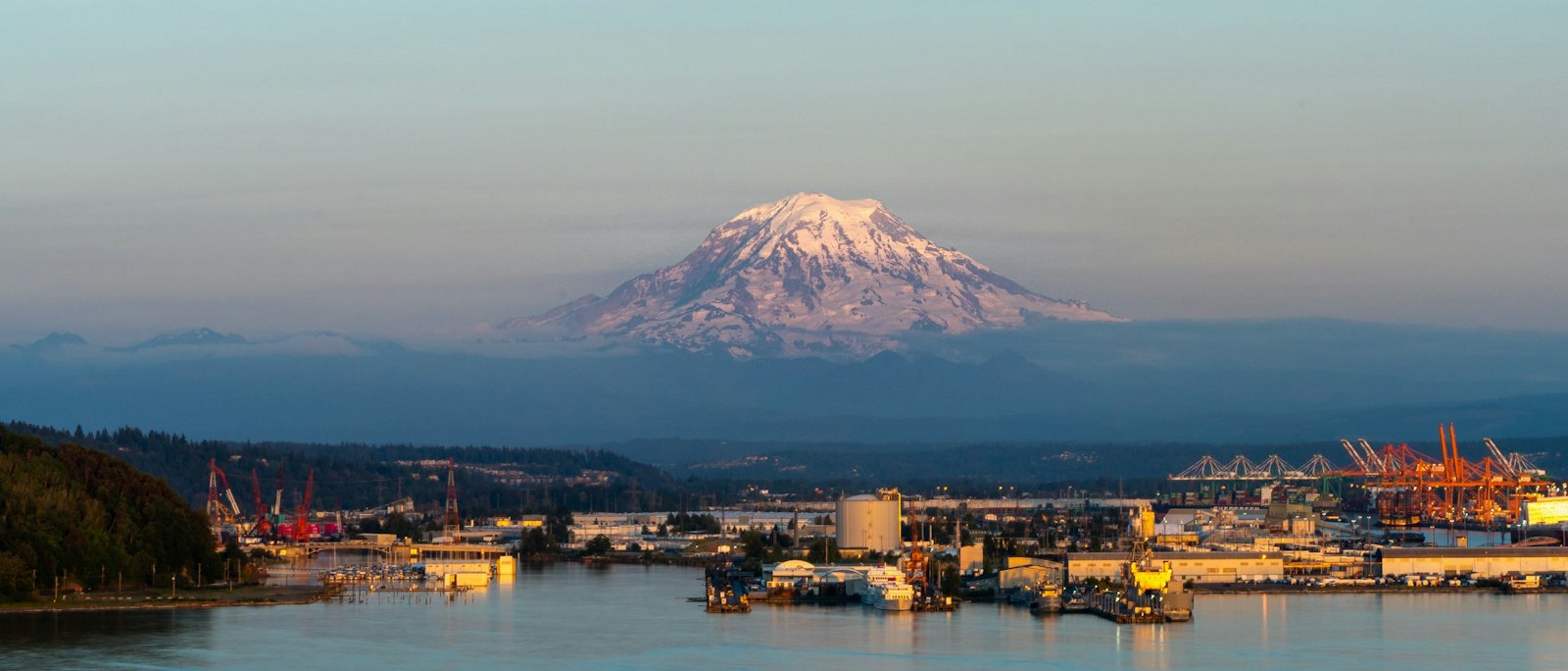 Industrial waterfront at sunset with Mount Rainier glowing in the distance