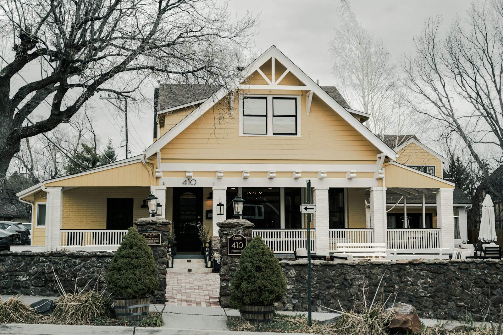 Yellow Craftsman-style house with a wide front porch and stone planters